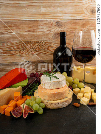 Cheese plate of color cheeses variety, yellow, white and blue gorgonzola platter with red wine glass 125787609