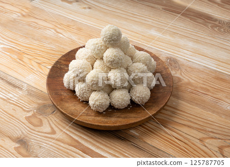 Coconut candies pile, coco ball. White truffle ball, indian ladoo or laddu with sweet cream and coco 125787705