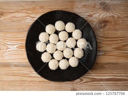 Coconut candies pile, coco ball. White truffle ball, indian ladoo or laddu with sweet cream and coco 125787706