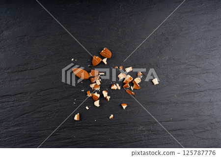 Crushed almonds, nut pieces, sliced scattered almond seeds and cut kernels collection on black background 125787776