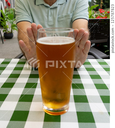 Reject a glass of beer, man refusing alcohol, stop drinking, sobriety concept, saying no to beer glass 125787823