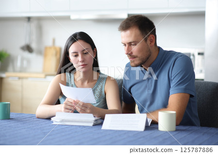 Serious interracial couple reading bank letter Serious interracial couple reading bank letter 125787886