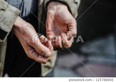 The photo shows old, dirty hands stretched out in a plea for alms, revealing a life of hardship. Dirty old man's worn-out hands ask for alms. The photo shows old, dirty hands stretched out in a plea for alms, revealing a life of hardship. Dirty old man's worn-out hands ask for alms. 125788008