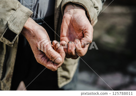 Wrinkled and covered in dirt, the hands tremble as they reach out, symbolizing desperation and struggle. The hands of a beggar ask for alms. Wrinkled and covered in dirt, the hands tremble as they reach out, symbolizing desperation and struggle. The hands of a beggar ask for alms. 125788011