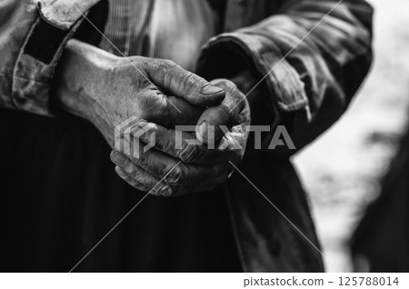 The homeless man's hands are caked with dirt and grime, rough from the cold. His hands reveal a harsh life spent on the streets.  125788014