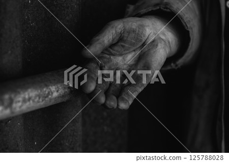 The hands are covered in dirt, marked by time and hardship. A dirty, labor-weary palm.  125788028