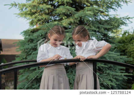 The girls watch the snail, holding their breath. Matching skirts flutter lightly, adding a sense of movement.  125788124