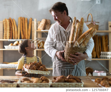 Bakery employees, father and daughter, offering bread, croissant and various baguettes for sale 125788847