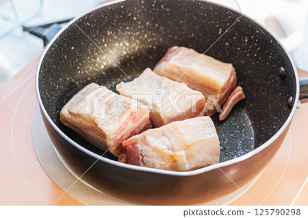Browning pork belly in a frying pan 125790298