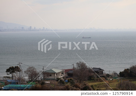 Beyond the residential area, you can see the sea, boats, the hazy sky, the mountains on the opposite shore, and the cityscape. Beyond the residential area, you can see the sea, boats, the hazy sky, the mountains on the opposite shore, and the cityscape. 125790914