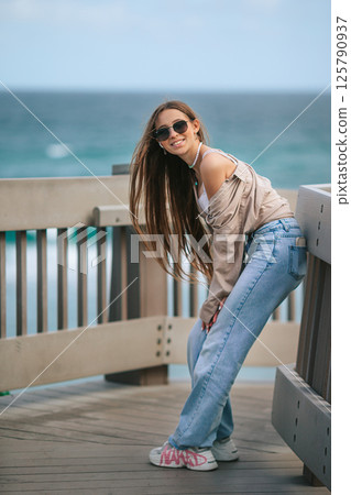Beautiful adorable girl outdoors in the park with ocean view Beautiful adorable girl outdoors in the park with ocean view 125790937
