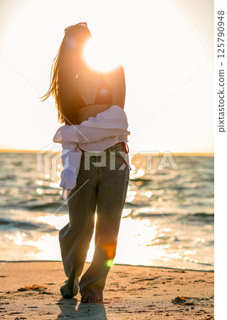 Silhouette of the beautiful girl enjoying beautiful sunset on the beach 125790948