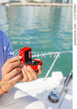 Close-up of a box with a ring in the hands of a man who is proposing 125790967