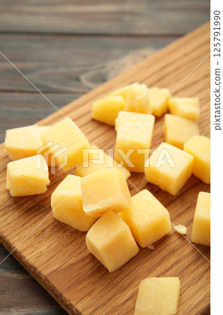 Cheese cubes on cutting board on brown background. Parmesan 125791990