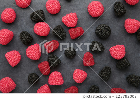 Red chewing sweets in the form of berries. Sweets in the form of raspberries on dark background. Space for text Red chewing sweets in the form of berries. Sweets in the form of raspberries on dark background. Space for text 125792002