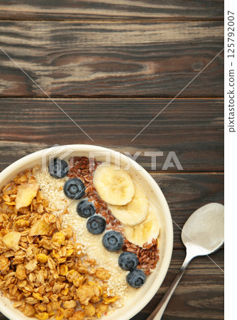 Oat raisin granola with fresh summer berries in a bowl on brown wooden background. Concept of healthy breakfast food, clean eating, dieting 125792007