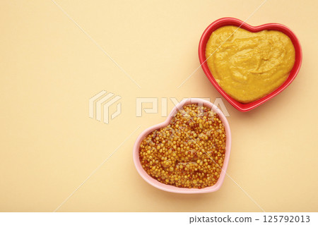 Dijon mustard with french mustard on beige background. Space for text Dijon mustard with french mustard on beige background. Space for text 125792013