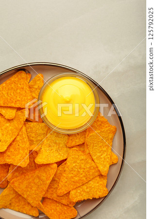 Tasty nachos with cheese sauce on light background. Vertical photo Tasty nachos with cheese sauce on light background. Vertical photo 125792025