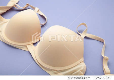 Beige female bra on purple background. Compression bra for breast. Top view 125792030