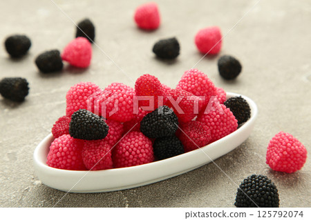 Raspberry and blackberry candy on plate on grey background. Top view Raspberry and blackberry candy on plate on grey background. Top view 125792074