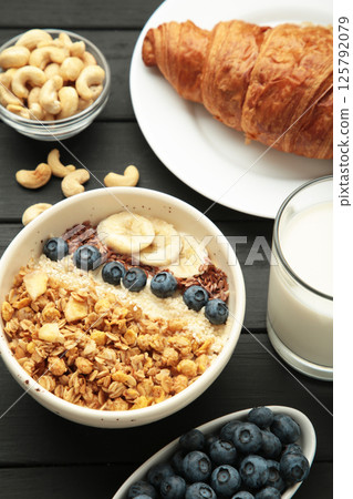 Beautiful morning breakfast with fresh croissants, granola with yoghurt and berries and fruit on plate. Vertical photo Beautiful morning breakfast with fresh croissants, granola with yoghurt and berries and fruit on plate. Vertical photo 125792079