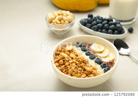 Oat raisin granola with fresh summer berries in a bowl on light background. Space for text 125792080