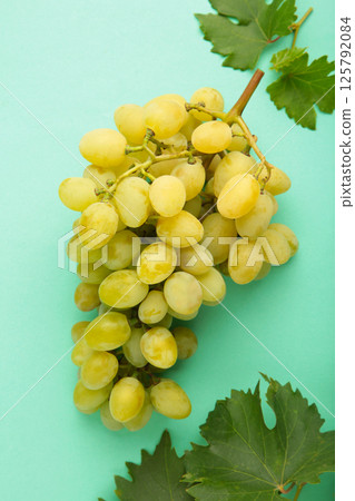 Green grape with leaves on mint background. Top view Green grape with leaves on mint background. Top view 125792084