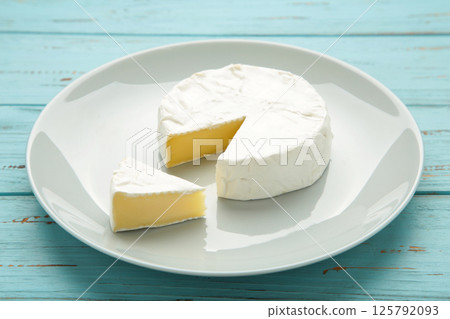 Slice camembert cheese on plate on blue wooden background. 125792093