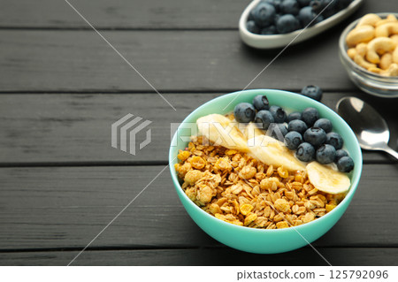 Oat raisin granola with fresh summer berries in a bowl on black wooden background. Concept of healthy breakfast food, clean eating, dieting 125792096