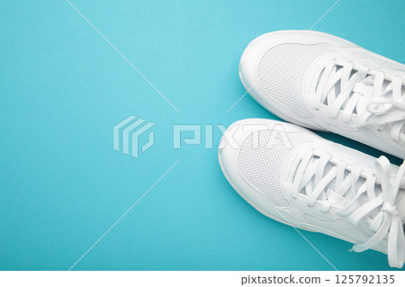 White sneakers on a blue background. Space for text White sneakers on a blue background. Space for text 125792135