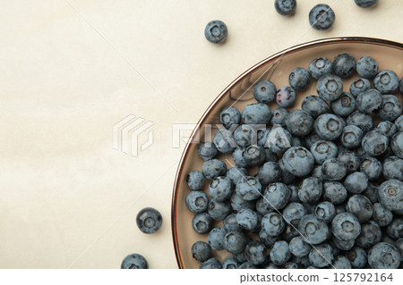 Beige ceramic bowl of fresh ripe blueberries on light background. Beige ceramic bowl of fresh ripe blueberries on light background. 125792164
