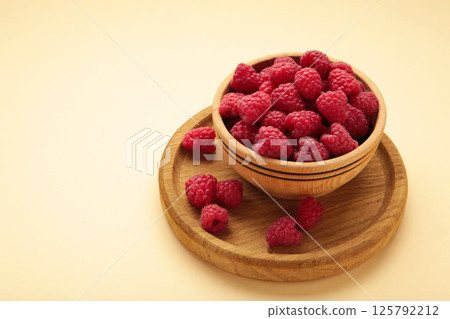 Raspberries in wooden bowl on beige background. Top view 125792212
