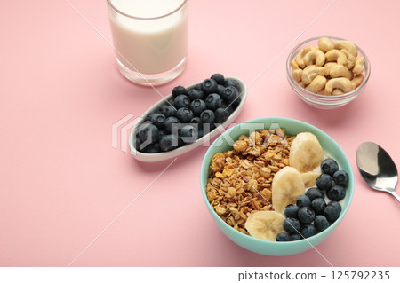 Oat raisin granola with fresh summer berries in a bowl on pink background. Concept of healthy breakfast food, clean eating, dieting 125792235