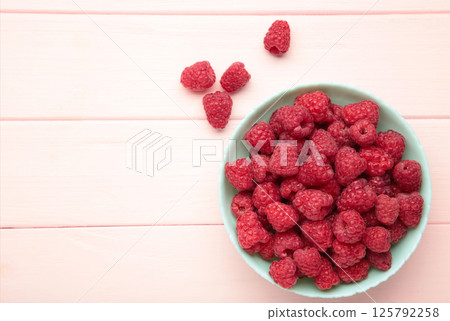 Raspberries in mint bowl on pink background. Space for text Raspberries in mint bowl on pink background. Space for text 125792258