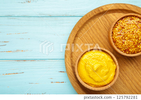 Dijon mustard with french mustard on blue wooden background. Dijon mustard with french mustard on blue wooden background. 125792281