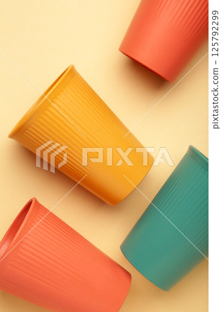 Eco plastic glass of various color on beige background. Space for text. Vertical 125792299