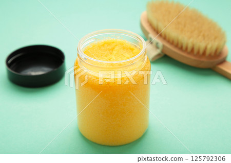 Handmade Sugar Peach Scrub With Argan Oil. Scrub with massage brush on mint background Handmade Sugar Peach Scrub With Argan Oil. Scrub with massage brush on mint background 125792306