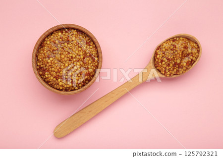 French grain mustard in bowl and spoon on pink background. French grain mustard in bowl and spoon on pink background. 125792321