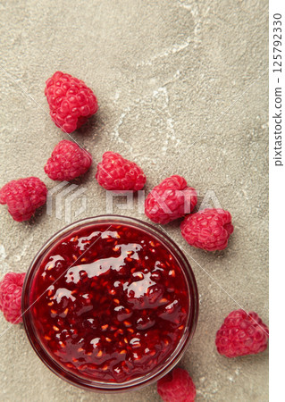 Raspberry jam jelly in bowl with berries on grey concrete background. Raspberry jam jelly in bowl with berries on grey concrete background. 125792330