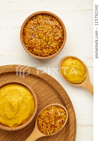 Dijon mustard with french mustard on white wooden background. Vertical photo 125792342