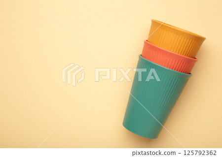 Eco plastic glass of various color on beige background 125792362