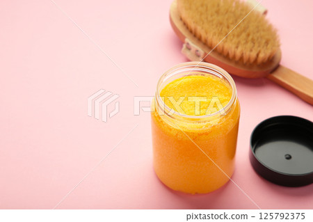 Handmade Sugar Peach Scrub With Argan Oil. Scrub with massage brush on pink background Handmade Sugar Peach Scrub With Argan Oil. Scrub with massage brush on pink background 125792375