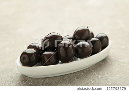 Fresh olives in white plate on grey concrete background. 125792379