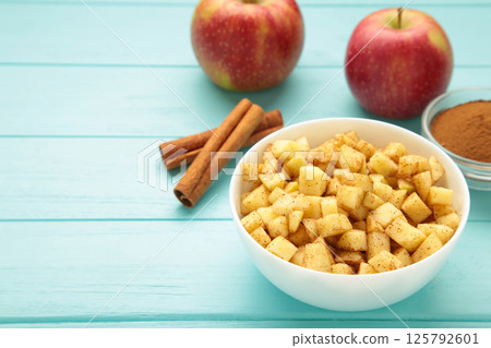 Apples with cinnamon on plate on blue background. Red apples with cinnamon sticks and star anise. Apples with cinnamon on plate on blue background. Red apples with cinnamon sticks and star anise. 125792601
