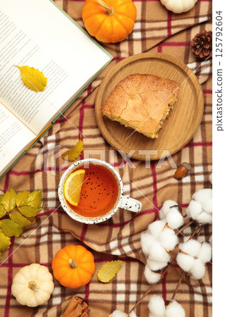 Hello autumn. Pumpkin, cup of tea, apple pie, autumn leaves, book on plaid. Happy Thanksgiving 125792604