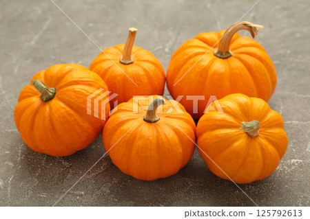 Mini orange pumpkins on grey concrete background. Mini orange pumpkins on grey concrete background. 125792613