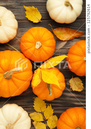 Autumn composition. Fresh orange and white pumpkin with autumn leaves on brown wooden background. Top view Autumn composition. Fresh orange and white pumpkin with autumn leaves on brown wooden background. Top view 125792614