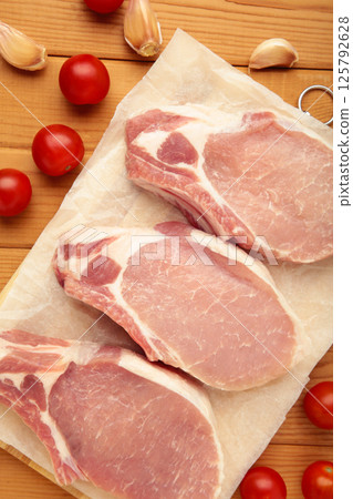 Sliced raw pork meat on cutting board on wooden background. Vertical photo Sliced raw pork meat on cutting board on wooden background. Vertical photo 125792628
