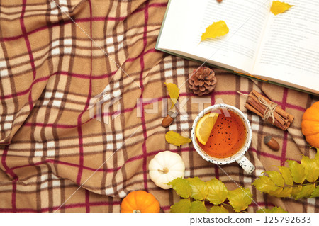 Hello autumn. Pumpkin, cup of tea, autumn leaves, book on plaid. Happy Thanksgiving 125792633