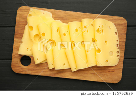 Cheese slices on cutting board on black wooden background. 125792689